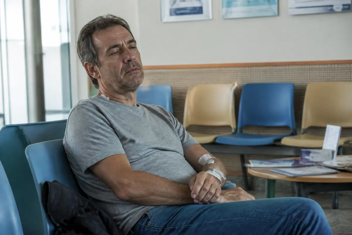 Homme assis, fatigué après une IRM, dans une salle d'attente médicale.