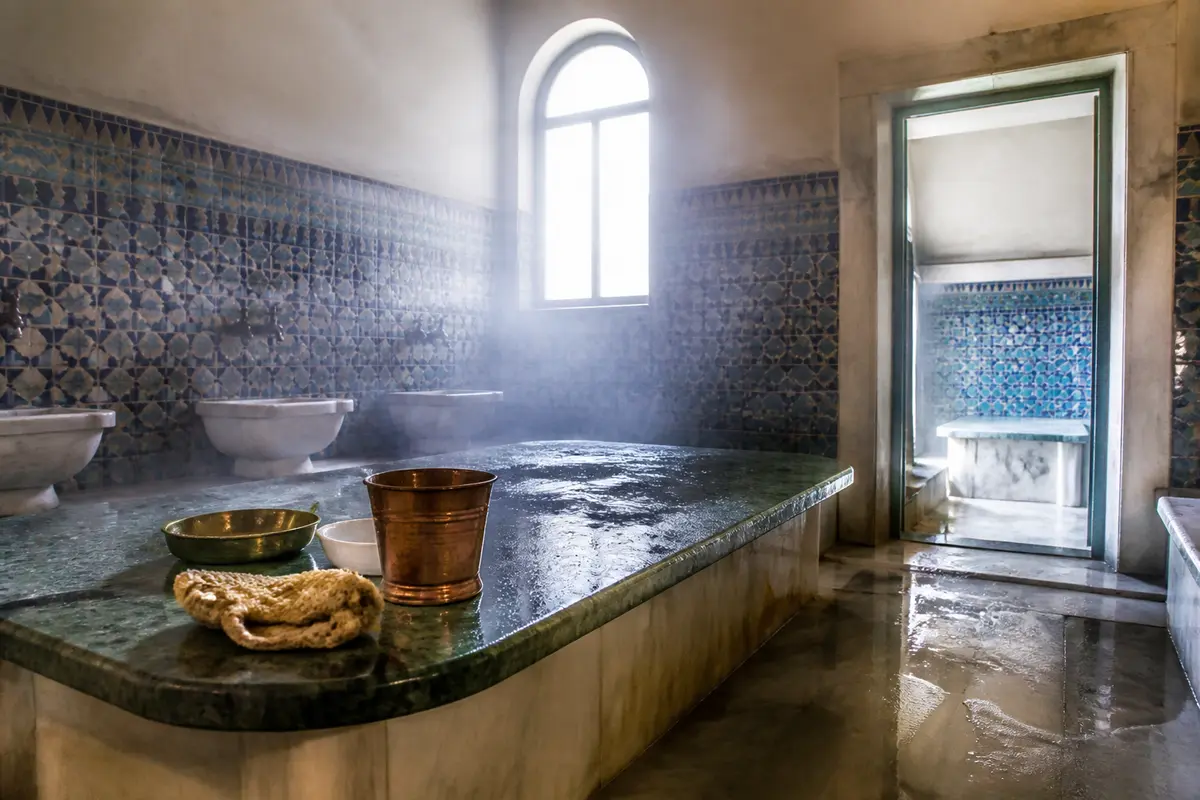 Salle traditionnelle d'un hammam à Clermont-Ferrand avec banc en marbre et accessoires en cuivre