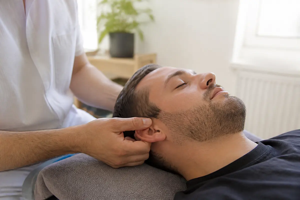 Thérapeute effectuant un massage de la trompe d'Eustache sur un patient détendu couchée